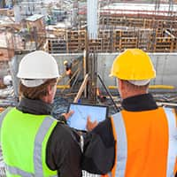 Two workers looking at tablet on construction site