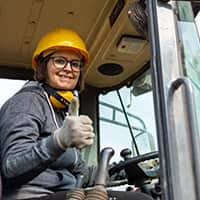 Woman crane driver wearing hard hat giving a thumbs up