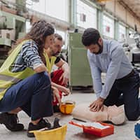 Three workers practicing CPR on a mannequin