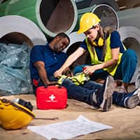 Woman in Safety Suit Using First Aid Kit to Help a Man in a Factory