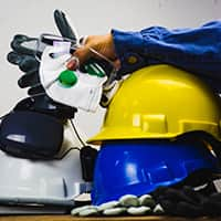 Stack of hard hats with a hand resting on top