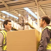 Two Workers Carrying a Box in a Warehouse