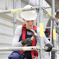 Lady working on scaffolding with a hammer