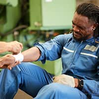 Worker having a bandage applied to his arm in a factory