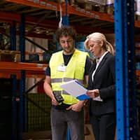 Worker and manager looking over report in warehouse