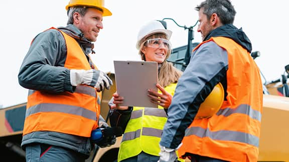 A trio of construction workers stands before a bulldozer, representing dedication and teamwork in the construction industry.