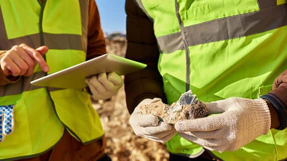 A person wearing a safety vest and yellow gloves is holding a hook, demonstrating safety and readiness for work.