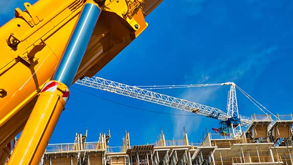 A crane stands prominently in front of a building that is currently under construction, showcasing ongoing development.