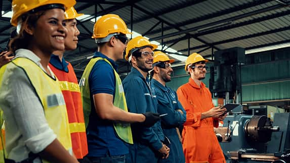 Several people in hard hats and safety vests, collaborating on a construction site, emphasizing safety and teamwork.